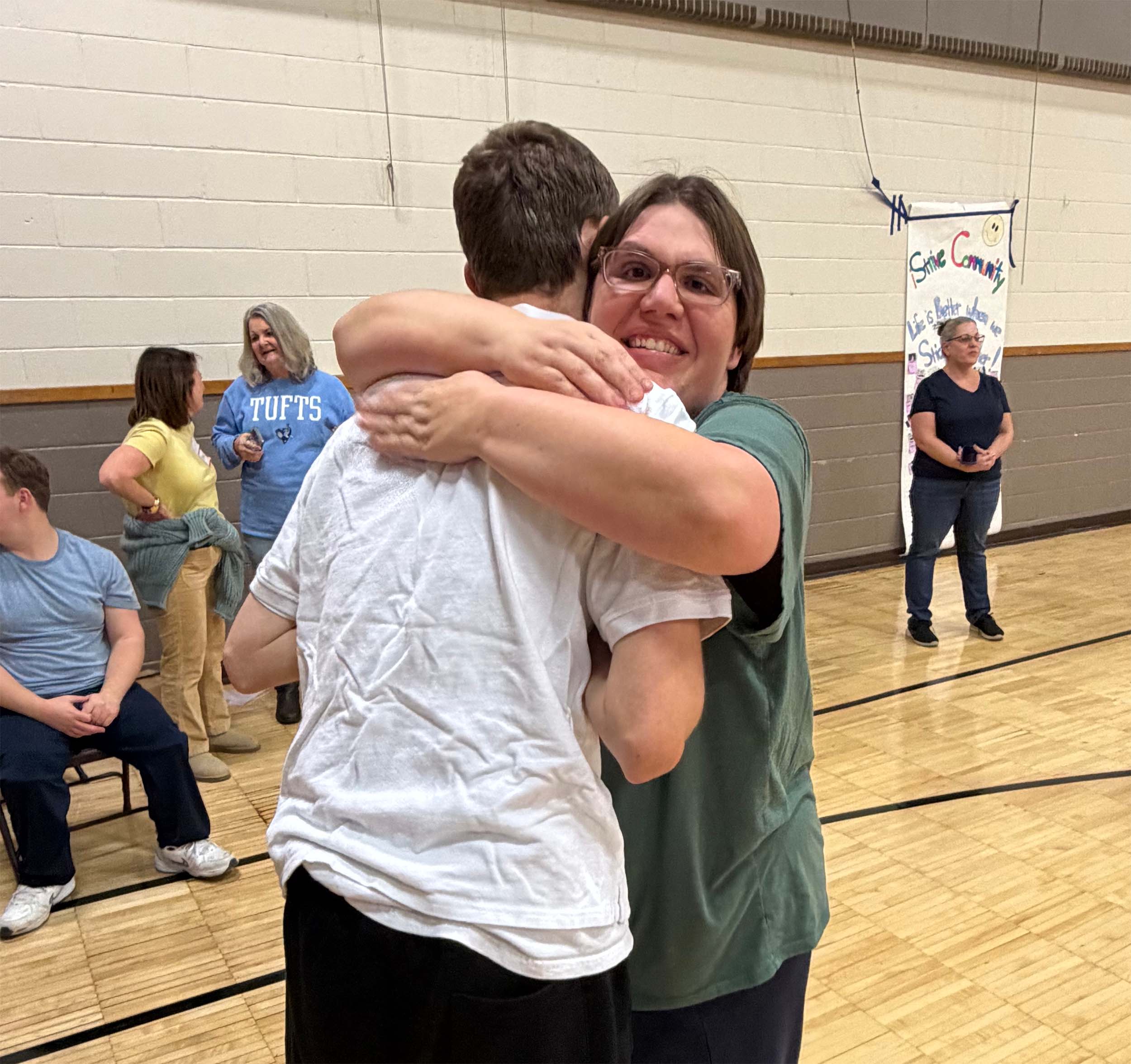 A person with special needs and a volunteer hug each other.